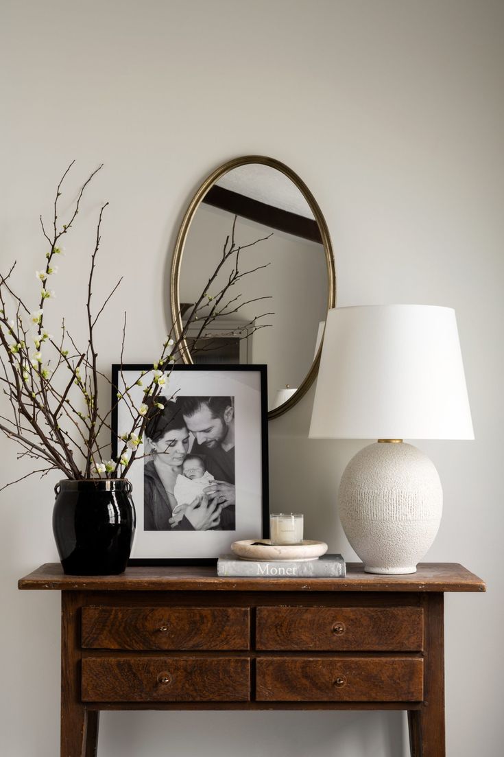 a table with a lamp, vase and pictures on it