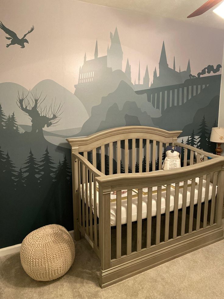 a baby crib in front of a wall with a castle scene painted on it