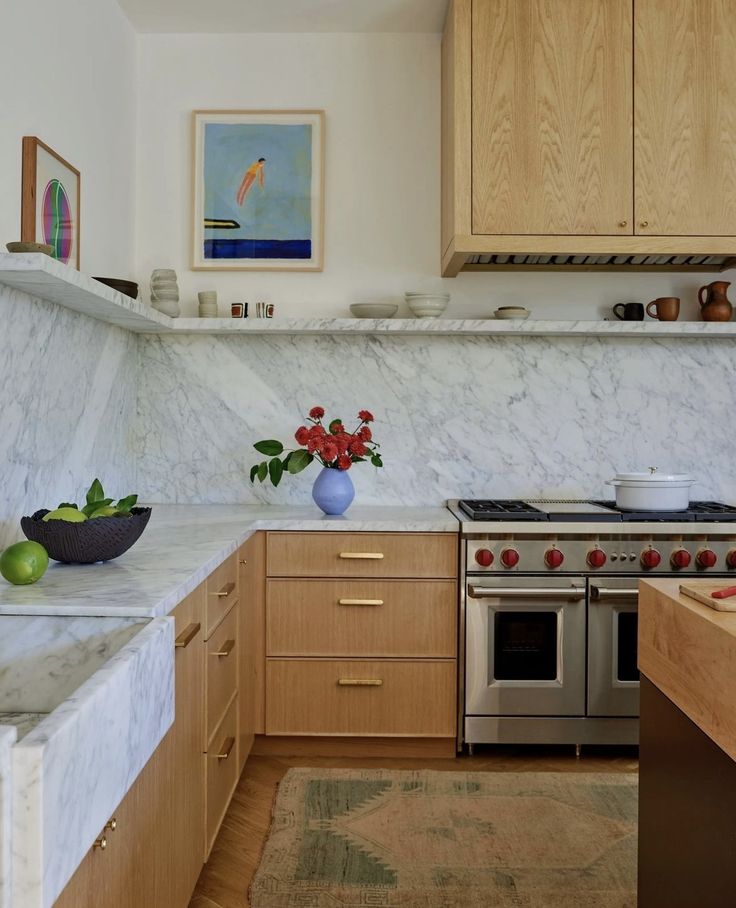 a kitchen with marble counter tops and wooden cabinets, along with a bowl of fruit on the counter