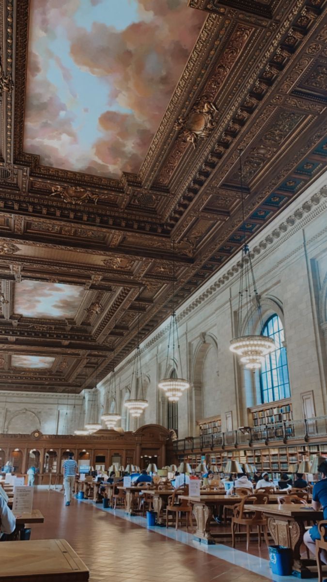 people sitting at tables in a large room with a sky painted on the ceiling above them