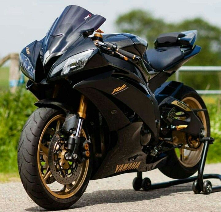 a black motorcycle parked on the side of a road next to a lush green field