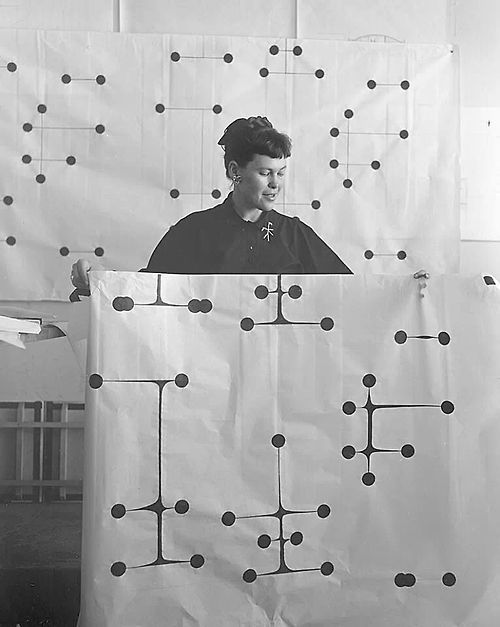 a black and white photo of a woman in front of a wall with circles on it