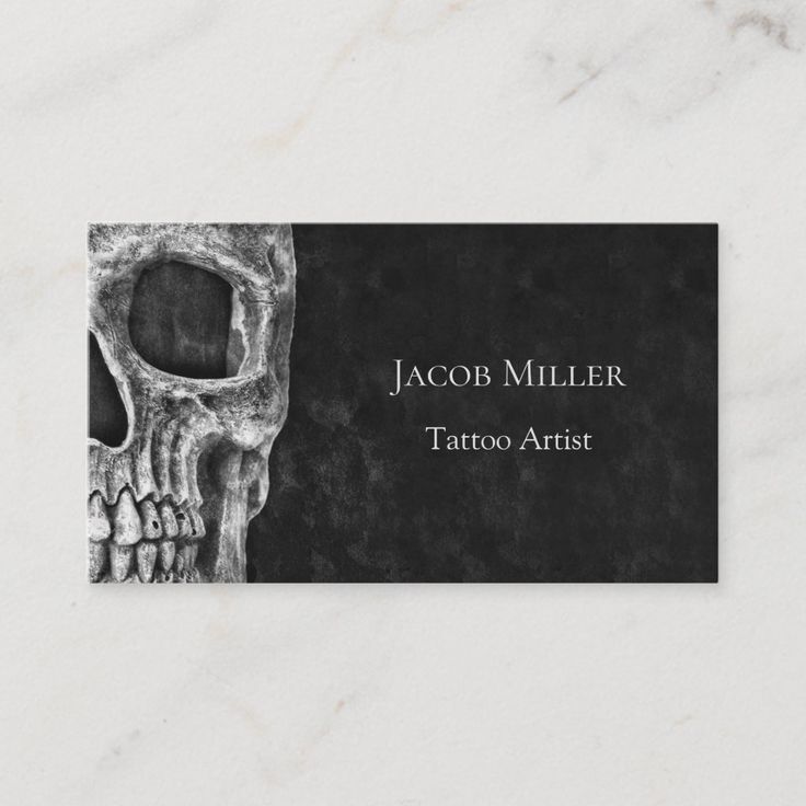 a black and white business card with a skull on the front, which reads your tattoo business