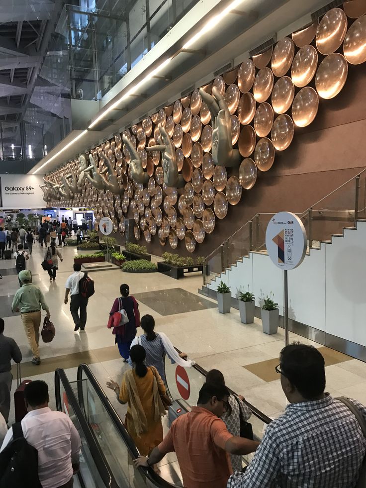 many people are walking up and down the escalator in an indoor mall area