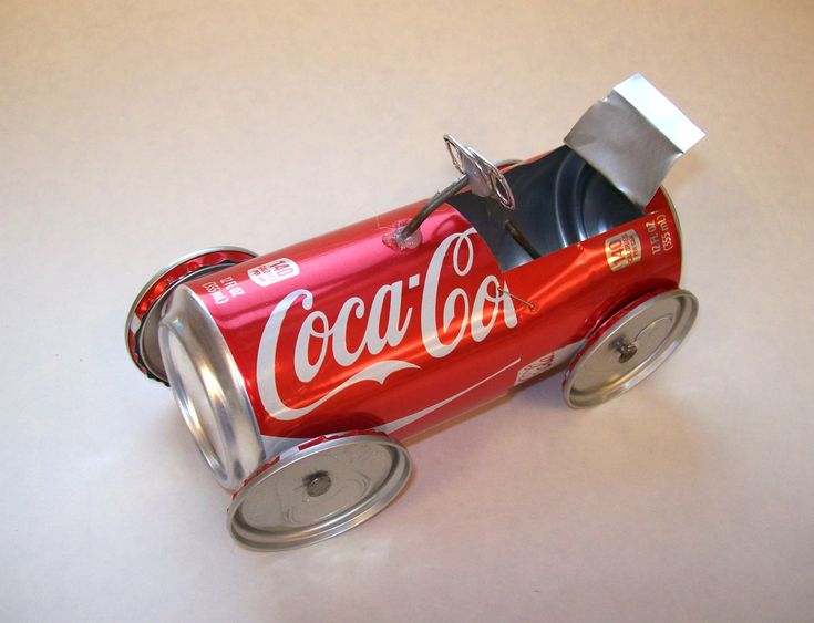 an open can of coca - cola sitting on top of a white table with the lid off