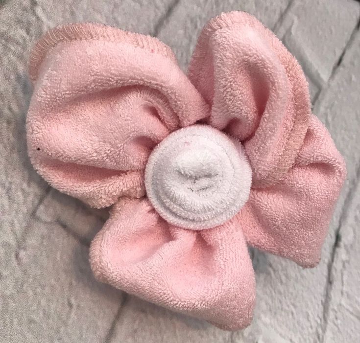 a pink flower with a white center laying on the ground next to a brick wall