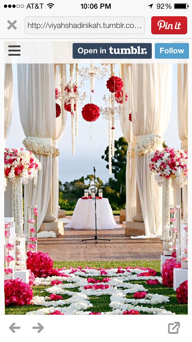 an outdoor wedding setup with white and pink flowers on the aisle, decorated with draping