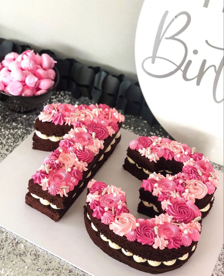 the number 50 is made out of chocolate and decorated with pink flowers in front of a cake