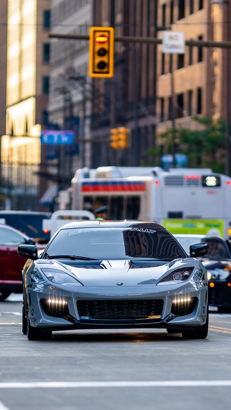 a silver sports car is driving down the street in front of traffic lights and buildings