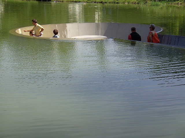 several people are sitting in a boat on the water while others stand around looking at it