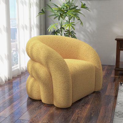 a yellow chair sitting on top of a hard wood floor next to a potted plant