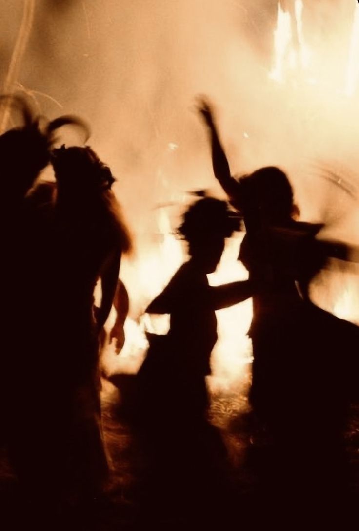 silhouettes of people dancing in front of a fire