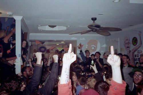 a large group of people in a room with their hands up