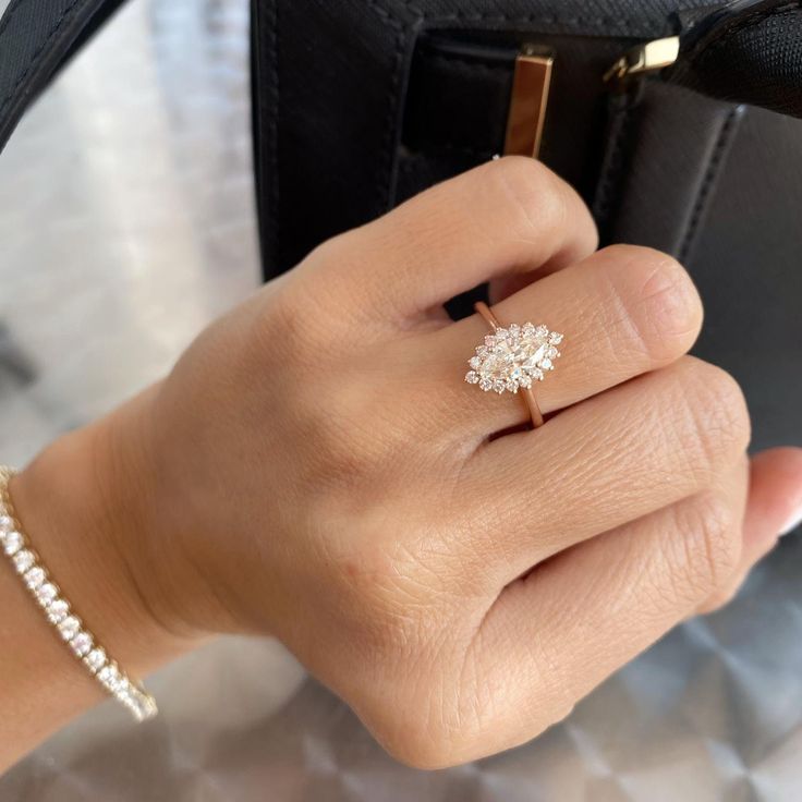 a woman's hand holding a black purse with a diamond ring on top of it