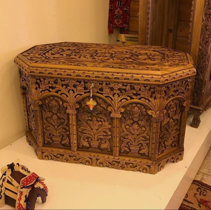 an ornate wooden chest with intricate carvings on the front and sides, next to a pair of shoes