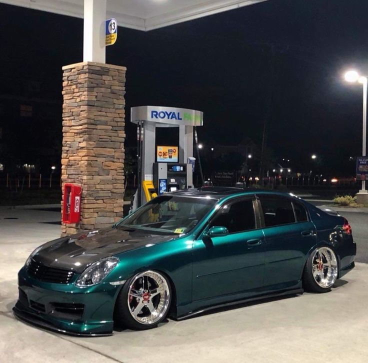 a green car parked in front of a gas station