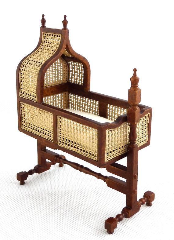 an antique wooden cradle with wicker baskets on it's sides and legs, against a white background