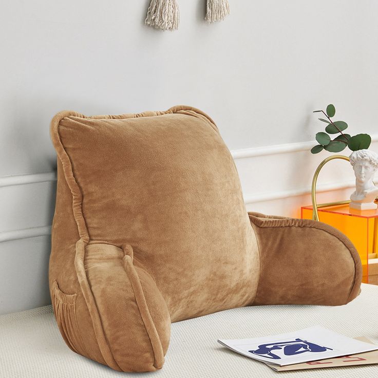 a large brown pillow sitting on top of a white table next to a vase with flowers