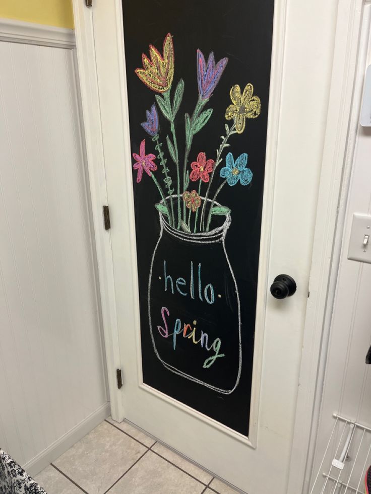 a chalkboard drawing of flowers in a vase on the door to a room with tile flooring