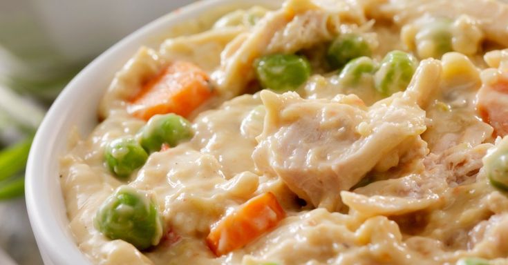 a close up of a bowl of food with peas and carrots on the side