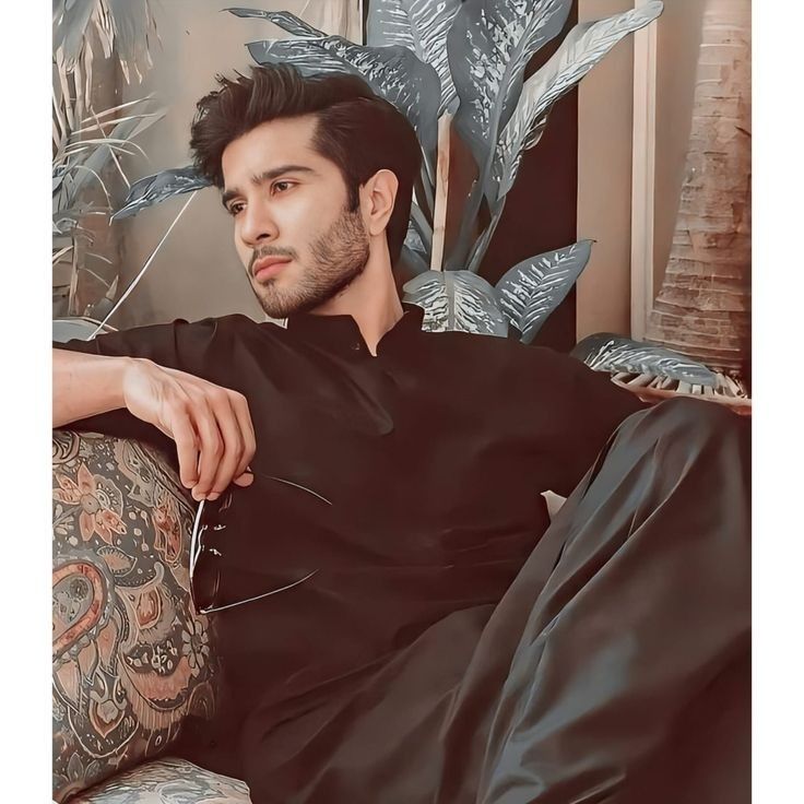 a man sitting on top of a couch next to a plant