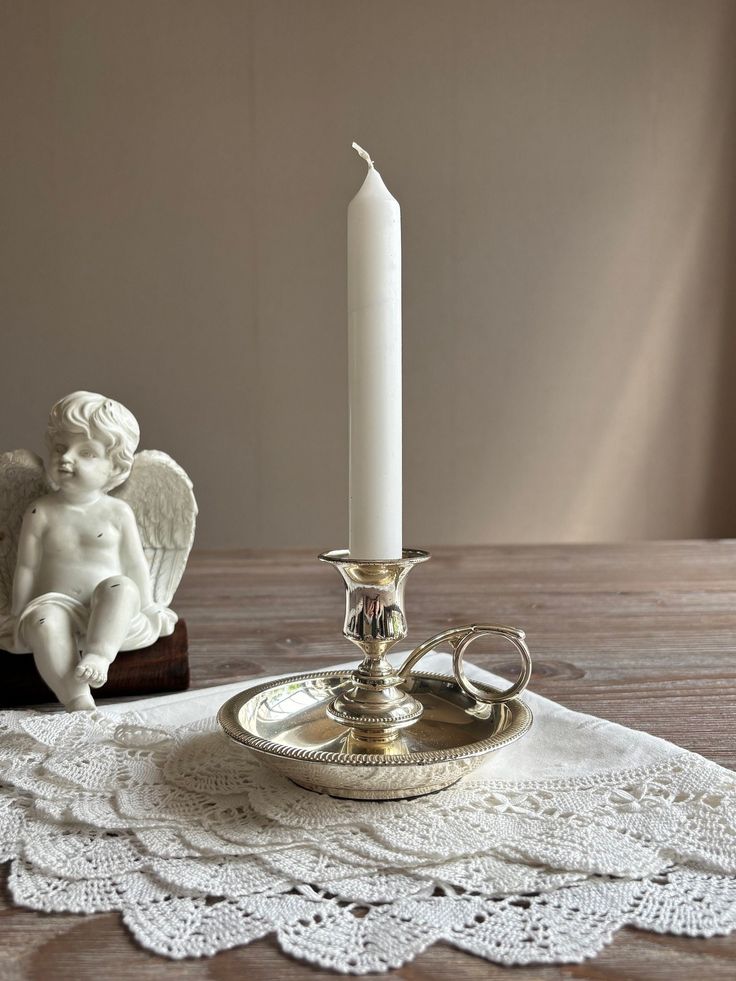 an angel figurine sitting on top of a table next to a candle