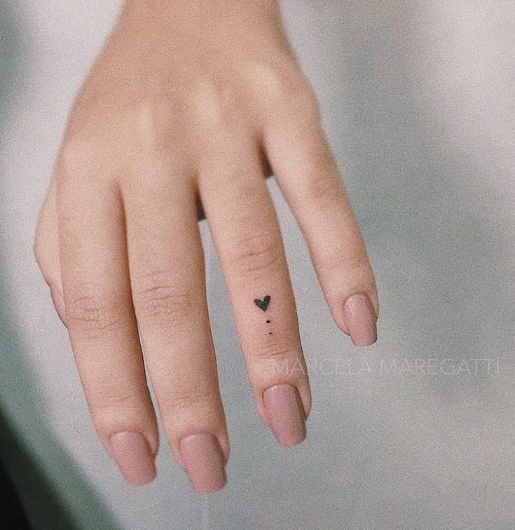 a woman's hand with a tiny heart tattoo on her left thumb and finger