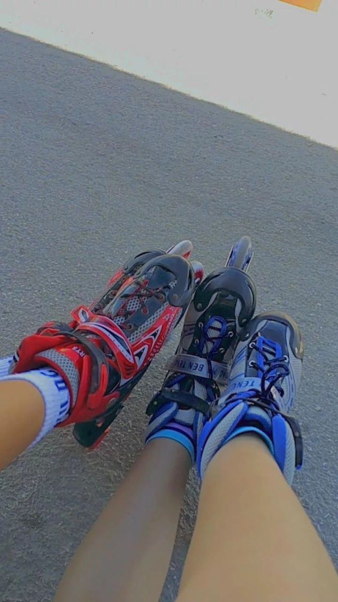 the legs and feet of a person riding a skateboard down a paved road with shoes on it