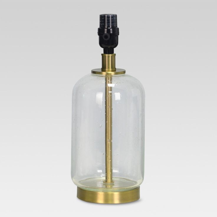 an empty glass bottle with a brass base and black top on a white background,