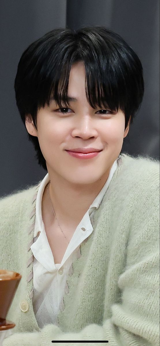 a woman with black hair is smiling and holding a coffee cup in her hand while looking at the camera