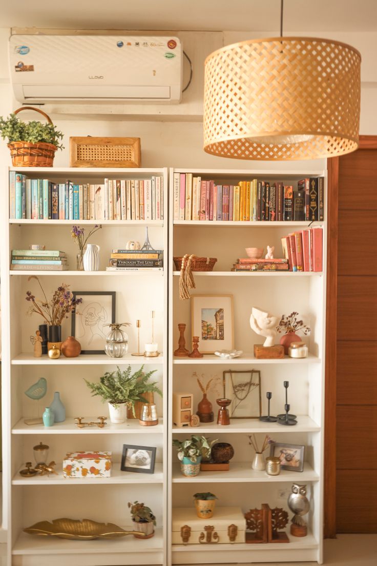 a white book shelf filled with lots of books next to a light hanging from the ceiling