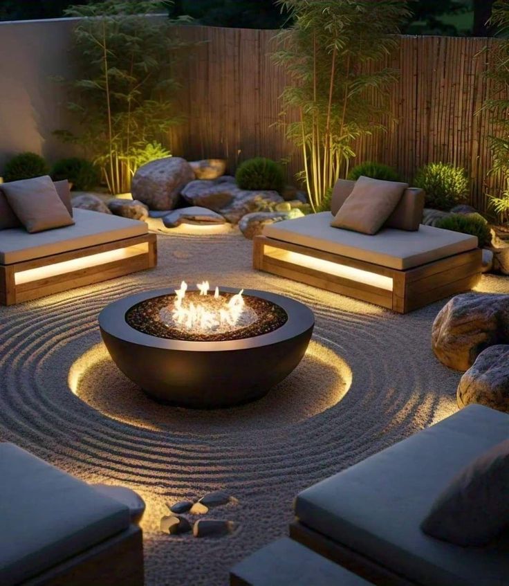 an outdoor fire pit surrounded by rocks and plants