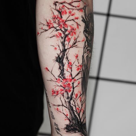 a person with a tattoo on their arm has a cherry blossom tree in the background