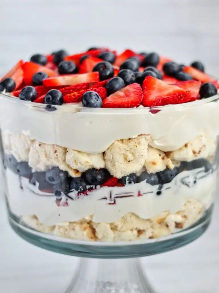 a trifle with berries and ice cream on top in a glass dish, ready to be eaten