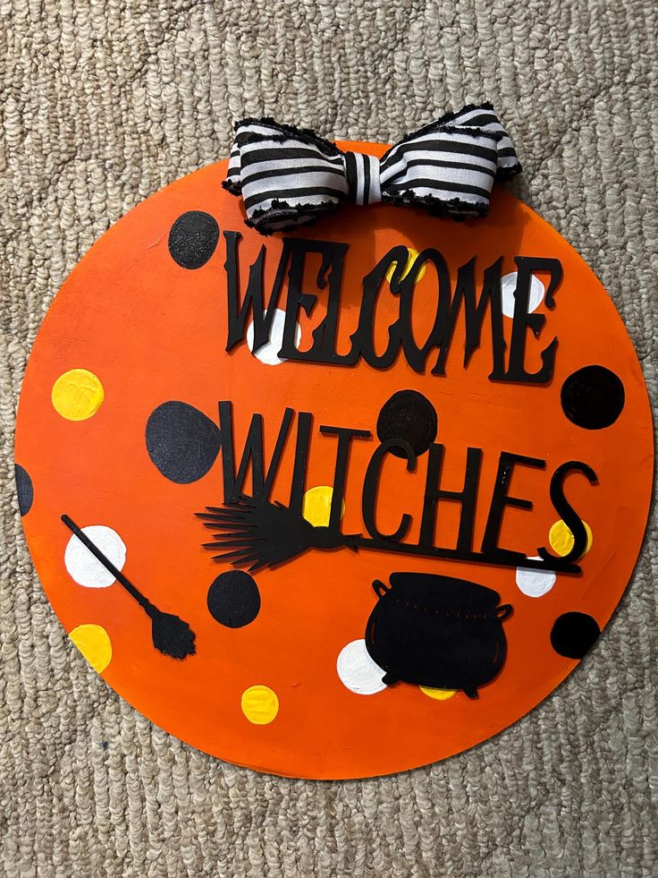 a welcome witches sign on the floor with black and white polka dots, striped bow