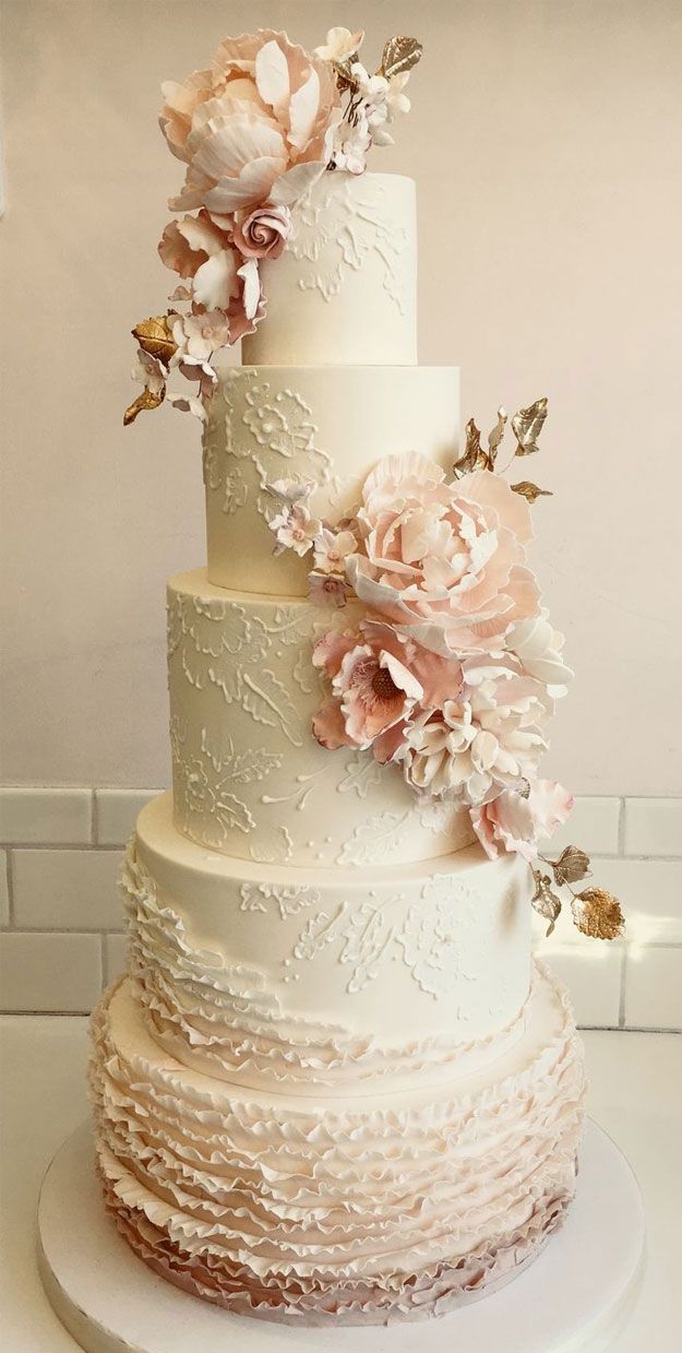 a three tiered wedding cake with pink flowers on the top and white icing