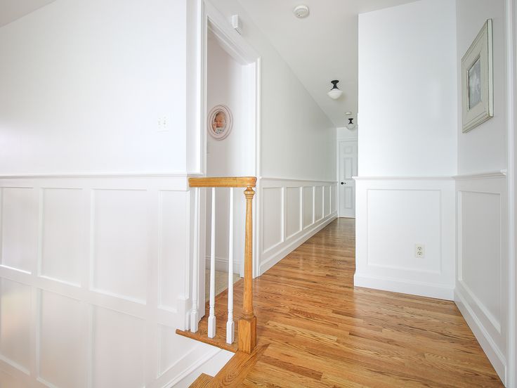 an empty room with white walls and wood floors is seen from the hallway to the second floor