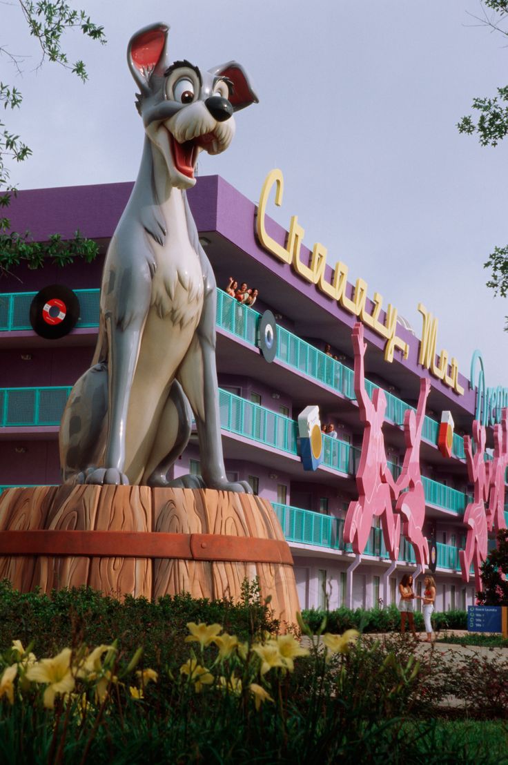 a large statue of a dog sitting on top of a wooden barrel in front of a building