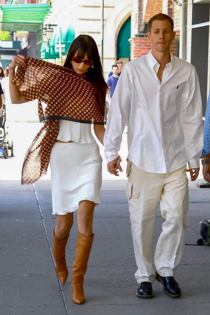 a man and woman are walking down the street together, one is carrying a scarf