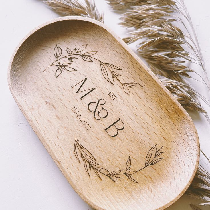 a wooden spoon with the name and date engraved on it next to some dried grass