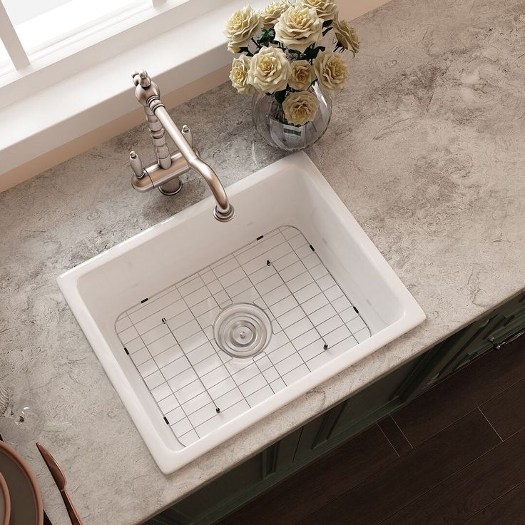 a white sink sitting on top of a counter next to a vase filled with flowers