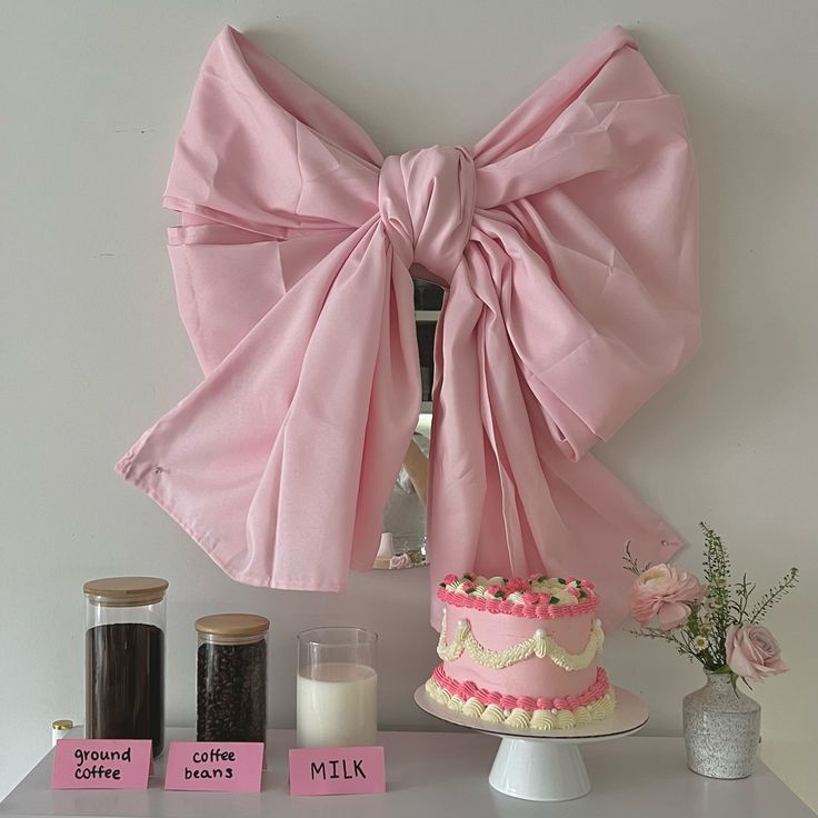 a pink bow is hanging on the wall above a cake