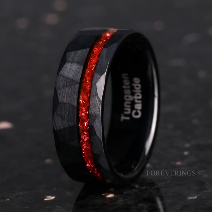 black ceramic ring with red glitter inlays on the outside and inside, sitting on a dark surface