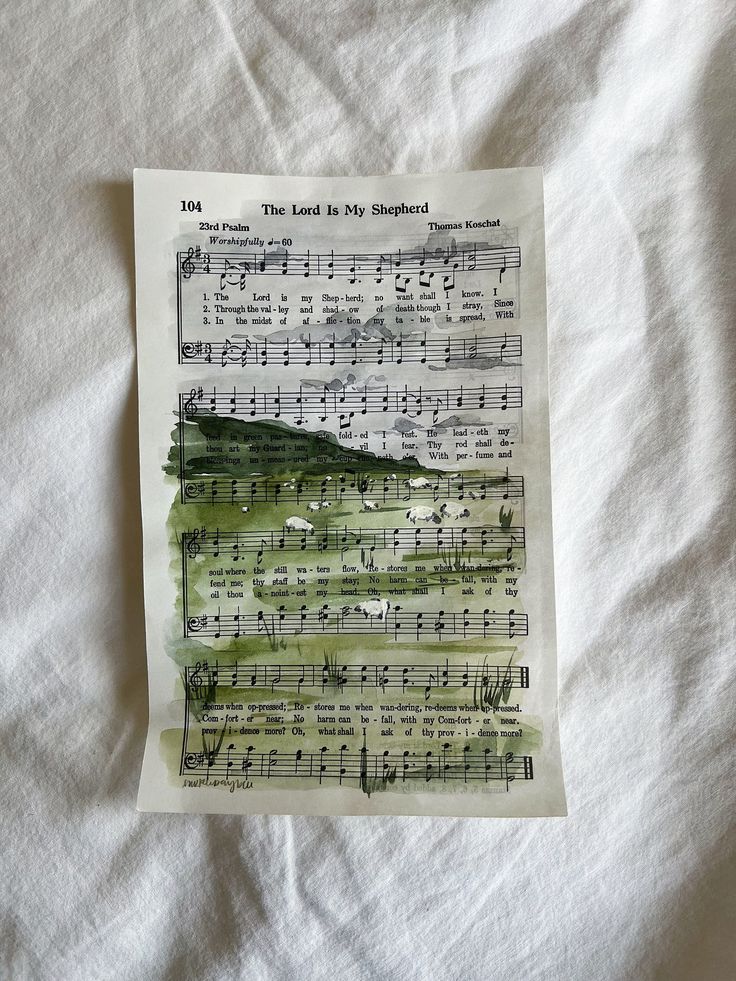 an old sheet of music is laying on a bed with white sheets and green ink