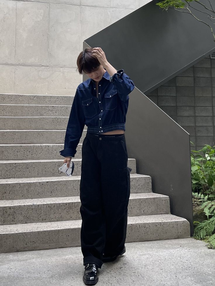 a woman standing in front of some stairs with her hand on her head and looking down