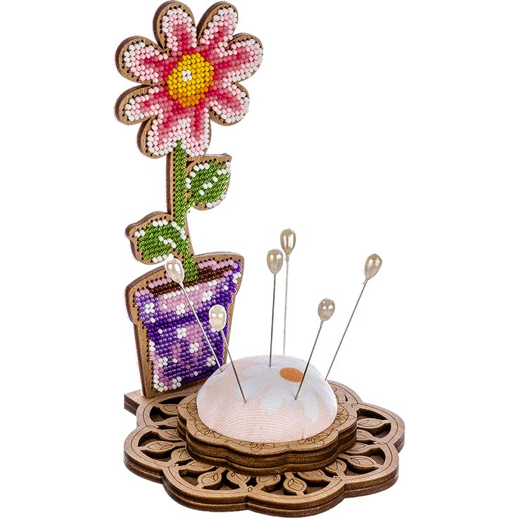 a flower pot with pins and needles in it sitting on top of a wooden stand