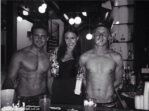 three shirtless men standing next to each other in front of a bar with drinks