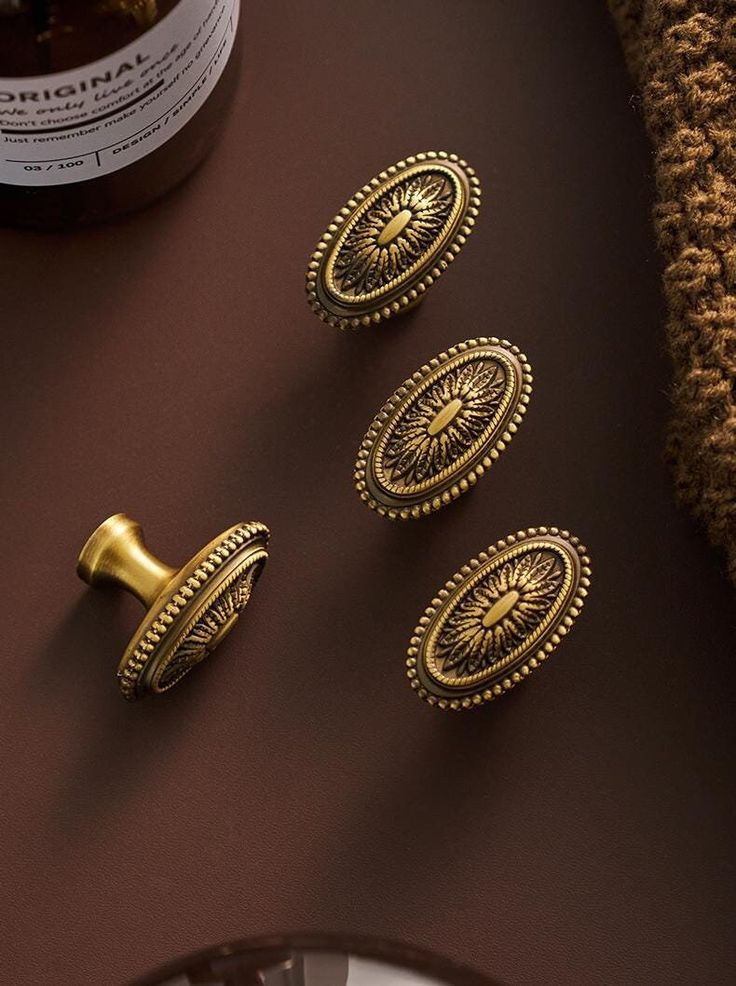 three brass cabinet knobs on top of a table next to a bottle of wine