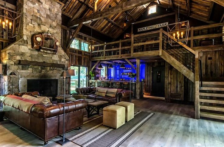 a large living room with stone fireplace and wooden ceiling beams, leather couches in front of an open fire place