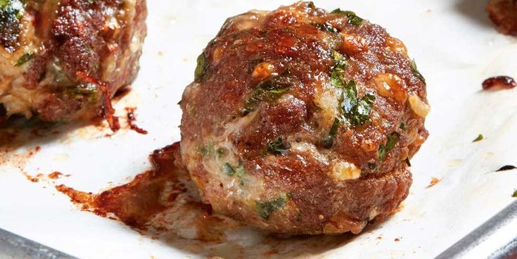 two meatballs sitting on top of a pan covered in sauce and seasoning sprinkles